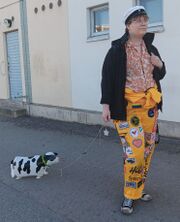 Picture of Elina wearing a student cap and yellow student overalls walking a cow balloon